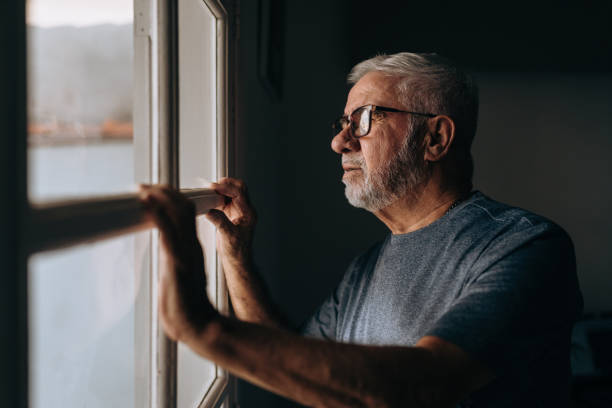 istock Elderly man looking out the window 1441546054