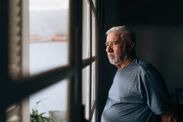 istock Elderly man looking out the window 1441546081