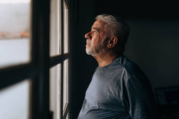istock Elderly man looking out the window 1441546089