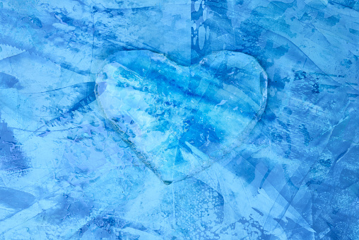 Piece of ice in shape of heart, frozen heart, icy heart on a blue textured background, ice valentine