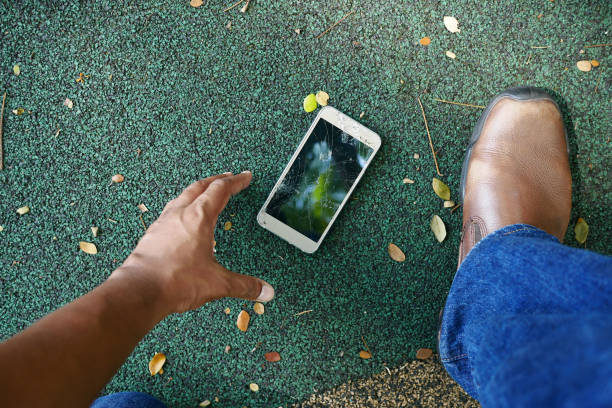 istock POV shot of hand picking broken smart phone from a floor 1441546491