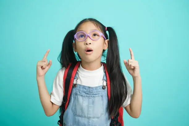 Photo of Close-up kid schoolgirl Pointing Fingers At Copy Space.