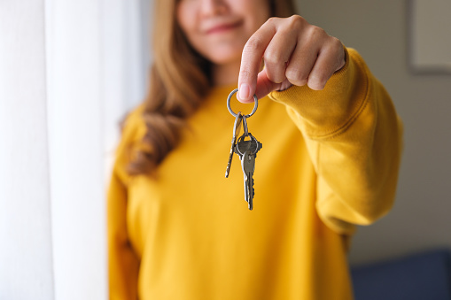 Closeup of a woman holding and showing the keys for real estate concept