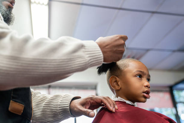 Black customers receive a haircut from barbers at a Black owned Barbershop A Black woman, young child, teenager, and adult male receives a haircut and a line-up from a classic barbershop. black barber stock pictures, royalty-free photos & images