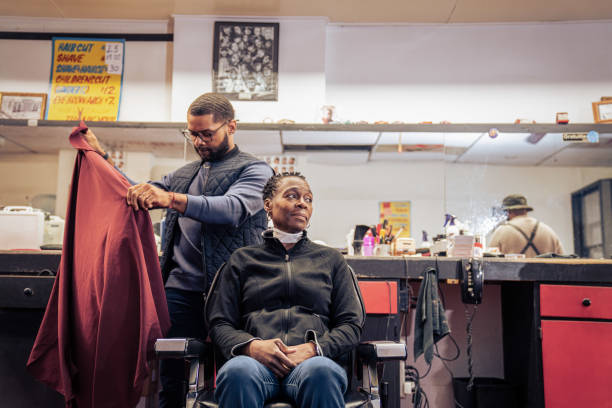 Black customers receive a haircut from barbers at a Black owned Barbershop A Black woman, young child, teenager, and adult male receives a haircut and a line-up from a classic barbershop. black barber stock pictures, royalty-free photos & images