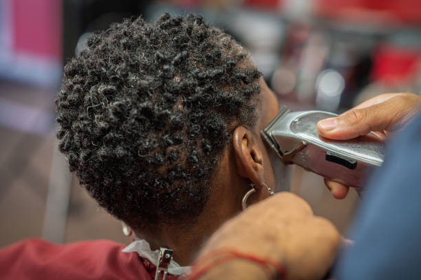 Black customers receive a haircut from barbers at a Black owned Barbershop A Black woman, young child, teenager, and adult male receives a haircut and a line-up from a classic barbershop. black barber stock pictures, royalty-free photos & images