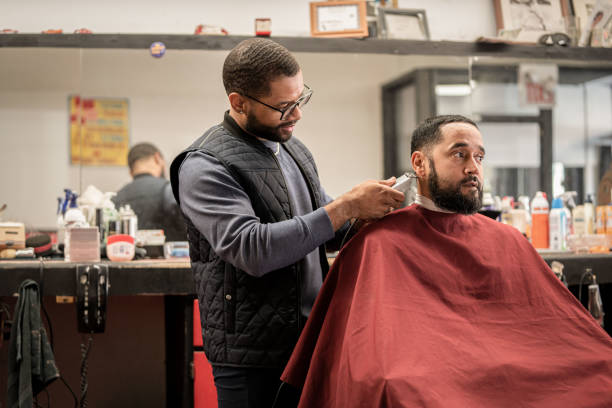 Black customers receive a haircut from barbers at a Black owned Barbershop A Black woman, young child, teenager, and adult male receives a haircut and a line-up from a classic barbershop. black barber stock pictures, royalty-free photos & images