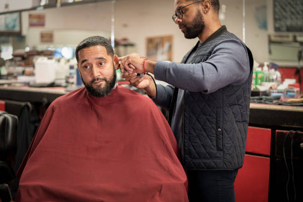 Black customers receive a haircut from barbers at a Black owned Barbershop A Black woman, young child, teenager, and adult male receives a haircut and a line-up from a classic barbershop. black barber stock pictures, royalty-free photos & images