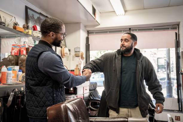 Black customers receive a haircut from barbers at a Black owned Barbershop A Black woman, young child, teenager, and adult male receives a haircut and a line-up from a classic barbershop. black barber stock pictures, royalty-free photos & images