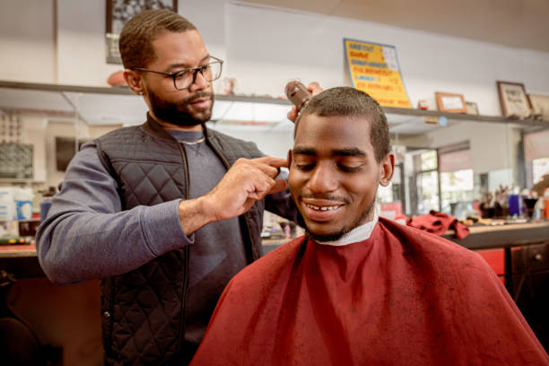Black customers receive a haircut from barbers at a Black owned Barbershop A Black woman, young child, teenager, and adult male receives a haircut and a line-up from a classic barbershop. black barber stock pictures, royalty-free photos & images