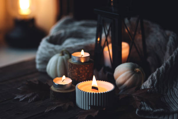 istock Cozy autumn composition with aromatic candle, pumpkins, wool sweater, leaves, cinnamon. Aromatherapy on a grey fall morning, home atmosphere of cosiness and relax. Wooden background close up. 1441550723