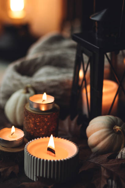 istock Cozy autumn composition with aromatic candle, pumpkins, wool sweater, leaves, cinnamon. Aromatherapy on a grey fall morning, home atmosphere of cosiness and relax. Wooden background close up. 1441550767