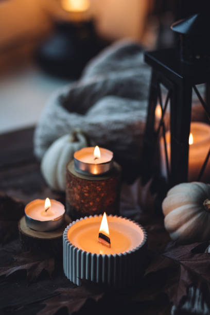 istock Cozy autumn composition with aromatic candle, pumpkins, wool sweater, leaves, cinnamon. Aromatherapy on a grey fall morning, home atmosphere of cosiness and relax. Wooden background close up. 1441550788