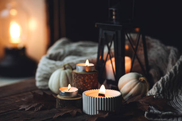 istock Cozy autumn composition with aromatic candle, pumpkins, wool sweater, leaves, cinnamon. Aromatherapy on a grey fall morning, home atmosphere of cosiness and relax. Wooden background close up. 1441550794
