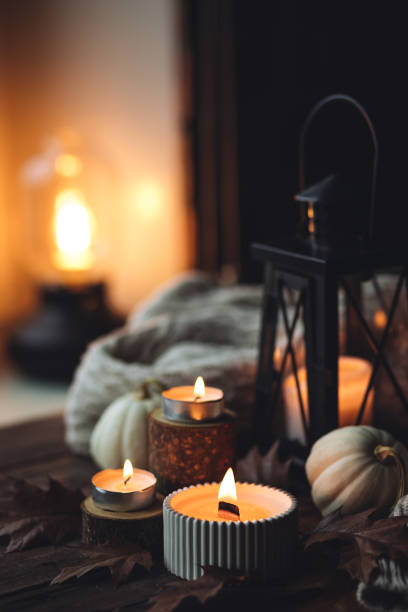 istock Cozy autumn composition with aromatic candle, pumpkins, wool sweater, leaves, cinnamon. Aromatherapy on a grey fall morning, home atmosphere of cosiness and relax. Wooden background close up. 1441550796