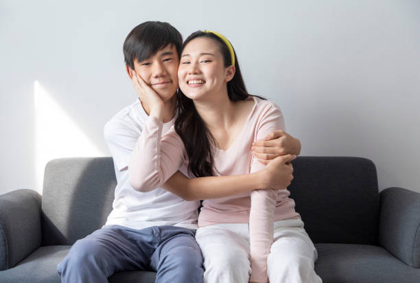 istock Asian brother and sister sit on sofa at home. 1441550800