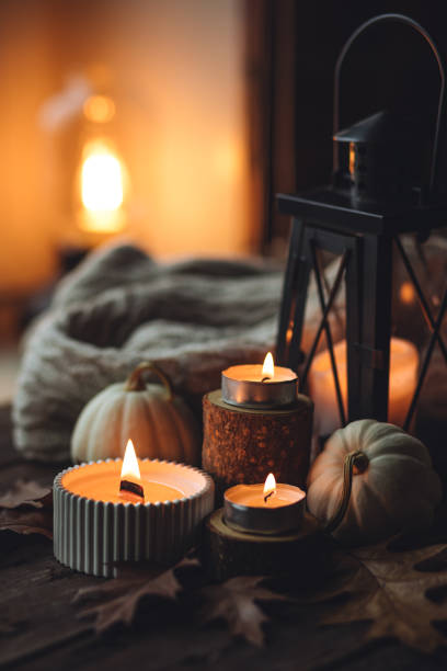 istock Cozy autumn composition with aromatic candle, pumpkins, wool sweater, leaves, cinnamon. Aromatherapy on a grey fall morning, home atmosphere of cosiness and relax. Wooden background close up. 1441550812