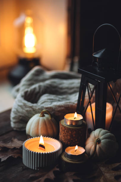 istock Cozy autumn composition with aromatic candle, pumpkins, wool sweater, leaves, cinnamon. Aromatherapy on a grey fall morning, home atmosphere of cosiness and relax. Wooden background close up. 1441550816