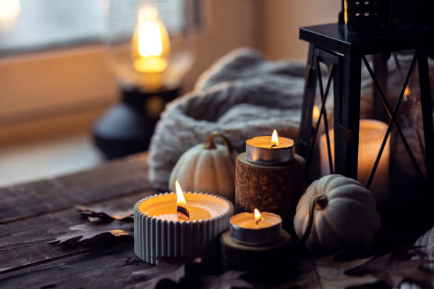 istock Cozy autumn composition with aromatic candle, pumpkins, wool sweater, leaves, cinnamon. Aromatherapy on a grey fall morning, home atmosphere of cosiness and relax. Wooden background close up. 1441550834