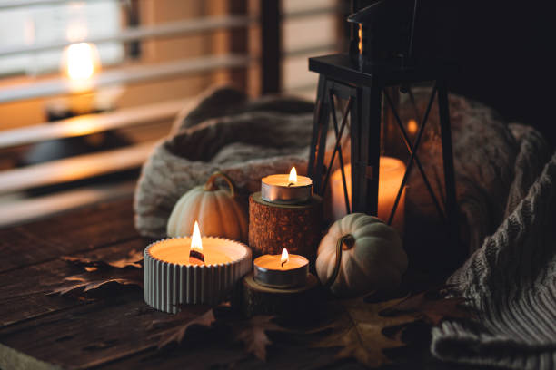 istock Cozy autumn composition with aromatic candle, pumpkins, wool sweater, leaves, cinnamon. Aromatherapy on a grey fall morning, home atmosphere of cosiness and relax. Wooden background close up. 1441550840