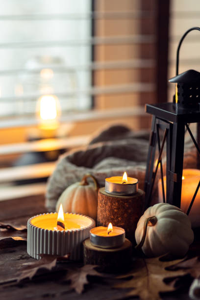 istock Cozy autumn composition with aromatic candle, pumpkins, wool sweater, leaves, cinnamon. Aromatherapy on a grey fall morning, home atmosphere of cosiness and relax. Wooden background close up. 1441550862