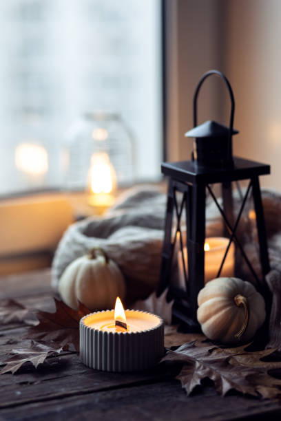 istock Cozy autumn composition with aromatic candle, pumpkins, wool sweater, leaves, cinnamon. Aromatherapy on a grey fall morning, home atmosphere of cosiness and relax. Wooden background close up. 1441550888