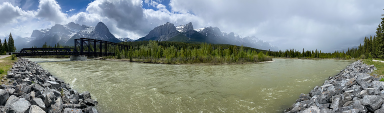 A cloudy sky over the Bow river and the engine bridge in Canmore in the summertime.