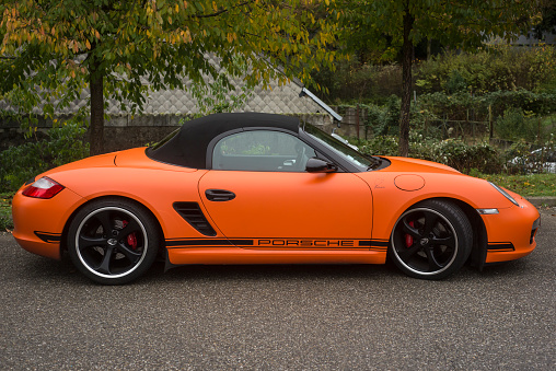 Mulhouse - France - 13 November 2022 - Profile view of orange porsche roadster convertible parked in the street