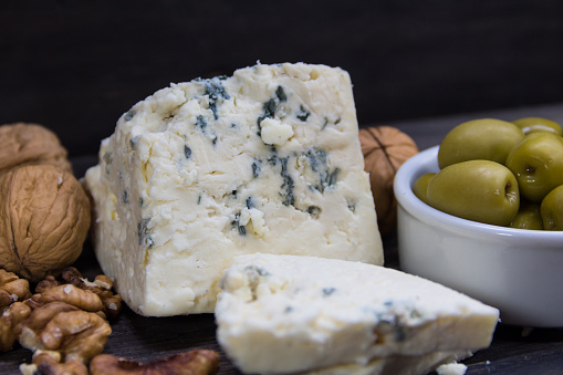 roquefort cheese with walnuts and olives on dark background