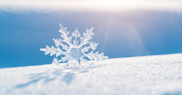 schöner eiskristall liegt im schnee und glitzert in der sonne, bokeh im blauen hintergrund - ice crystal winter nature ice stock-fotos und bilder