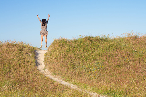 A closeup shot of an excited female jumping on a hill