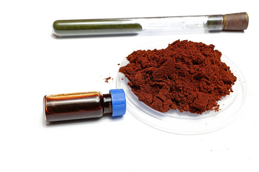 A closeup of a pile of dragon's blood reagent dust next to a small vial containing its liquid
