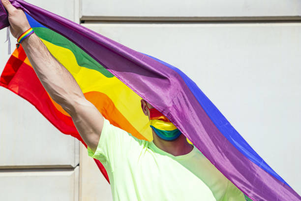 istock Man with a rainbow pride flag and a colorful mask 1441567609