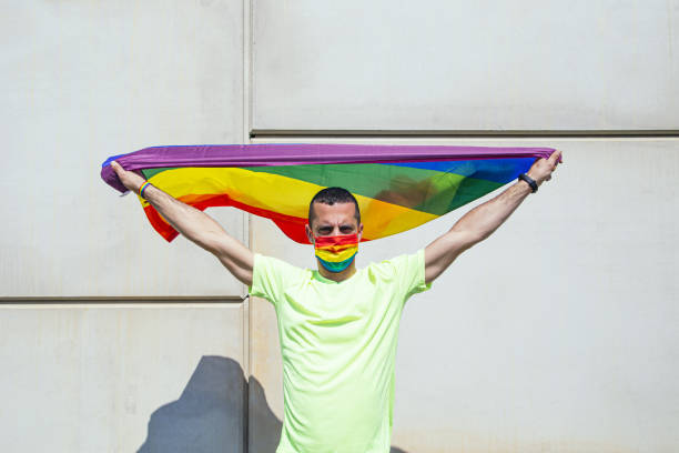istock Man with a rainbow pride flag and a colorful mask 1441567618