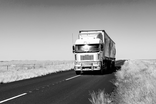 karoo, South Africa – January 06, 2021: Karoo, South Africa - March 17 2019: Long Haul overnight Trucking Logistics on a country highway road in South African Farmland region