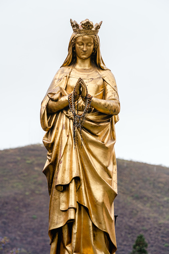 A vertical shot of the golden statue of Mary