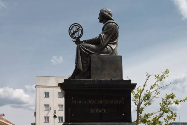 Warsaw, Poland – June 14, 2013: Nicolaus Copernicus Monument in Warsaw, Poland, bronze statue of Polish astronomer from 1830 holding a compass and armillary sphere, Staszic Palace