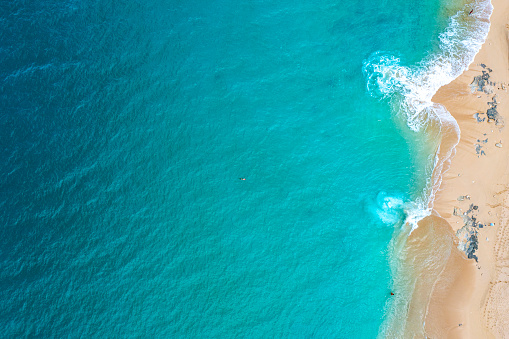 An aerial view of the sea waves touching the sandy beach of St. Martin, Baie Longue