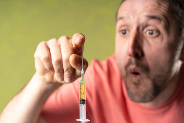istock Man touches doubtfully  the anti covid vaccine needle. 1441572599