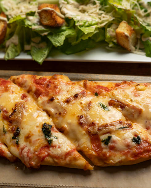 istock Vertical shot of a pizza and a caesar salad 1441573808