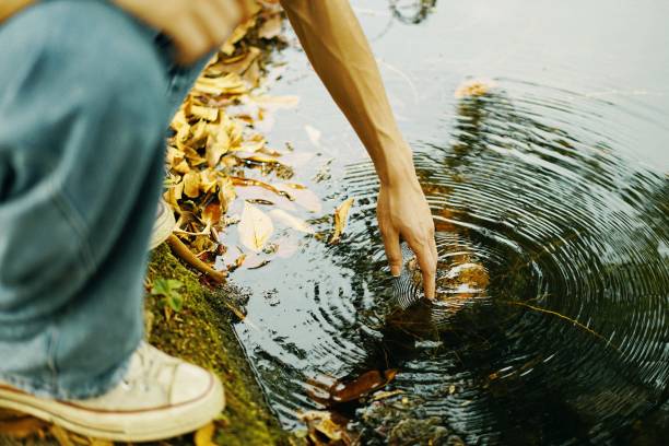 istock Boy leaning down to touch the water, artsy aesthetic 1441574226