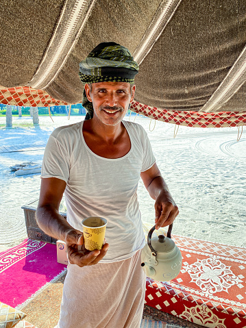Abu Dhabi, United Arab Emirates – September 24, 2021: An Emirati Man pouring traditional Karak Tea in Abu Dhabi, UAE, Sept 21