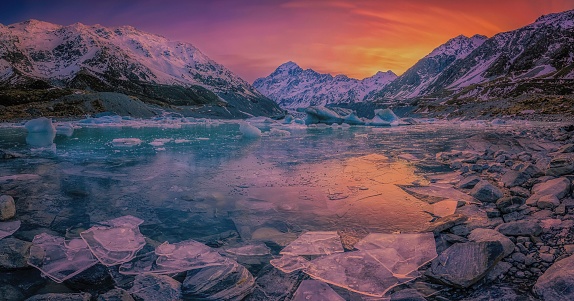 A mesmerizing sunset over the snowy hills with a frozen lake - great for a wallpaper