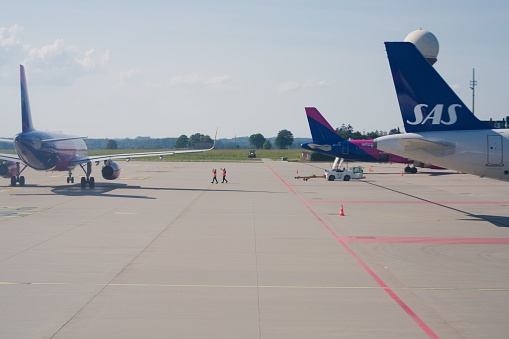 Gdansk, Poland – August 16, 2022: The Lech Walesa airport with planes on the board and technical crew waiving at a plane in the distance