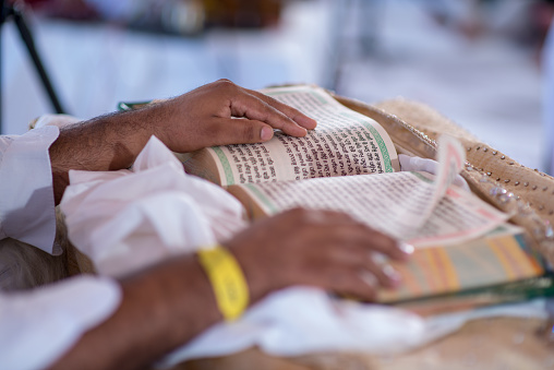 A closeup of a man reading the Granth Sahib at a traditional Indian wedding