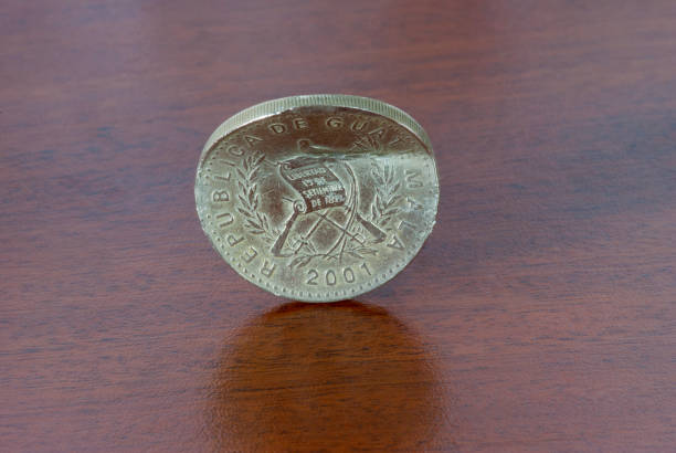 istock Broken coin from one Quetzal, Guatemala, 2001, on wood texture. 1441576332