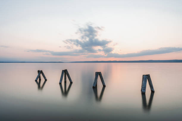 impressão do sol de pilares de madeira no lago de neusiedl (podersdorf am see, burgenland, áustria) - natural column - fotografias e filmes do acervo