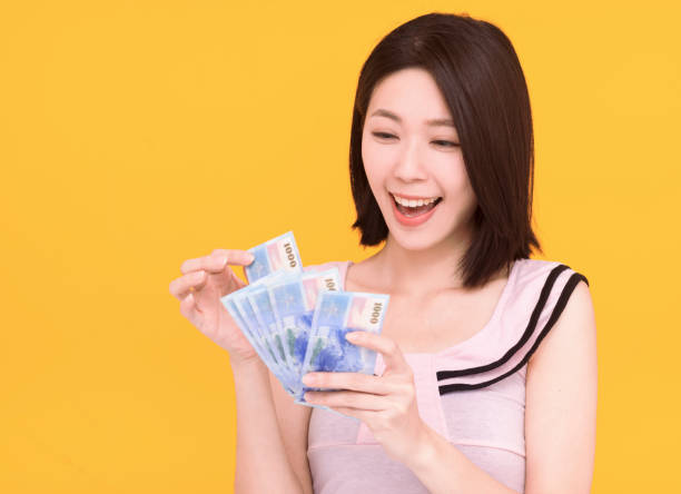 Jeune heureux comptant de l’argent et isolé sur fond jaune - Photo