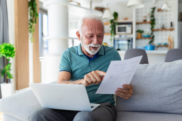 istock Surprised laughing happy old mature retired man looking through paper document, feeling excited analyzing financial information, getting taxes refund or bank loan approval at home. 1441578756