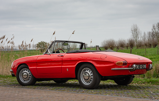 Buren, Netherlands – April 04, 2021: A red vintage car Alfa Romeo1750 Spider Duetto manufactured in the year 1969